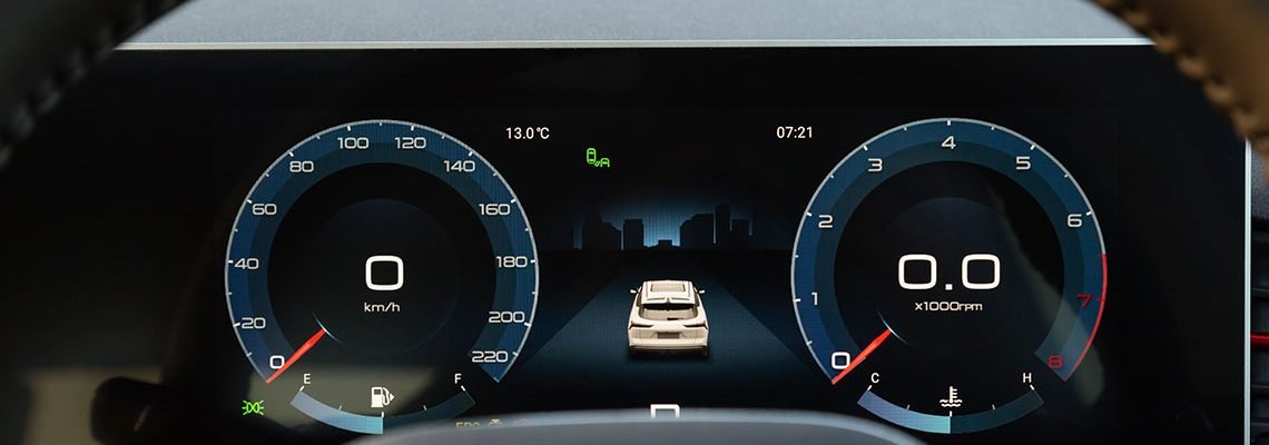 Close-up of a car dashboard displaying digital speedometer and tachometer, both at zero. A central screen shows a vehicle icon on a road, indicating a city backdrop.